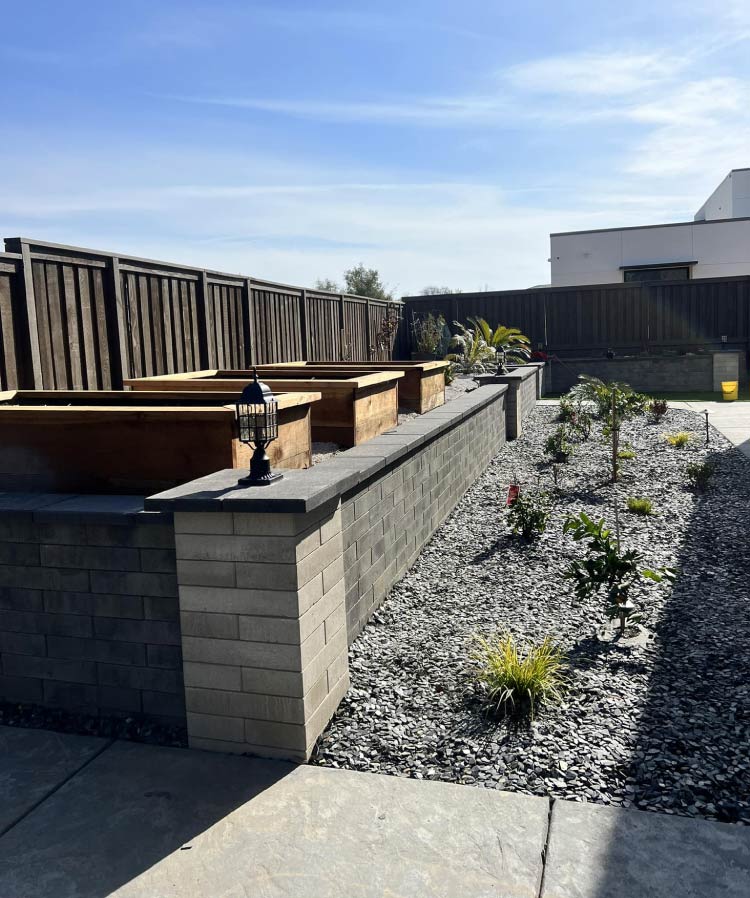 Large residential backyard design in El Dorado Hills featuring modern stone retaining walls and custom wooden raised garden planters.