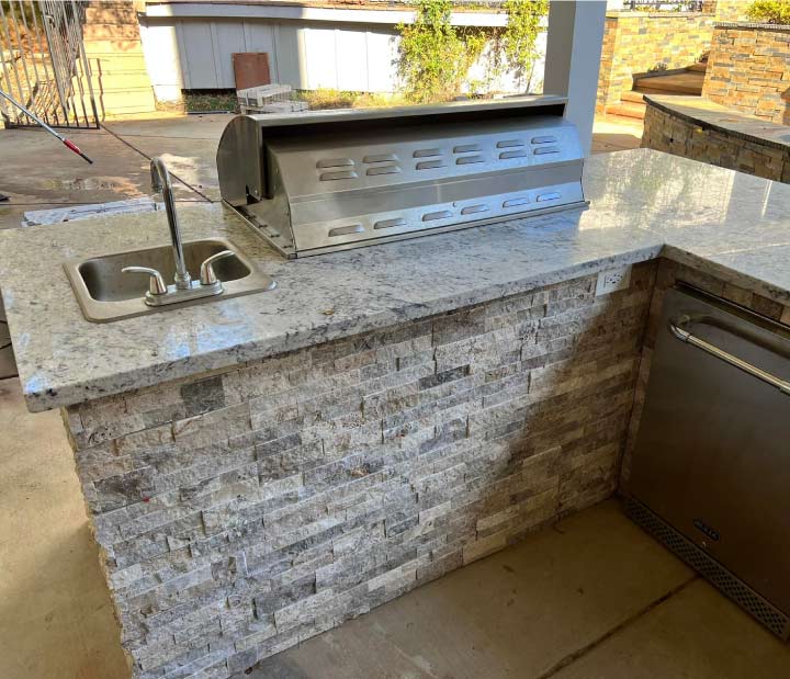 High-end outdoor kitchen installation in El Dorado Hills featuring a white granite countertop, integrated stainless steel sink, and custom grey stone masonry.